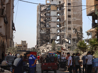 Palestinians are checking the rubble of buildings that were destroyed following an Israeli air strike on a residential building, amid the Is...