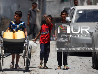 Palestinians are walking in front of a building damaged by Israeli bombardment in Nuseirat in the central Gaza Strip, on July 21, 2024, amid...