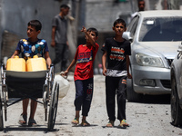 Palestinians are walking in front of a building damaged by Israeli bombardment in Nuseirat in the central Gaza Strip, on July 21, 2024, amid...