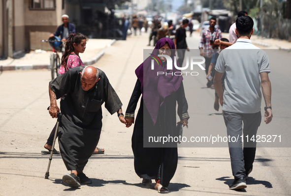 Palestinians are walking in front of a building damaged by Israeli bombardment in Nuseirat in the central Gaza Strip, on July 21, 2024, amid...