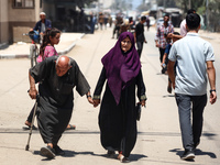 Palestinians are walking in front of a building damaged by Israeli bombardment in Nuseirat in the central Gaza Strip, on July 21, 2024, amid...