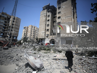 Palestinians are walking in front of a building damaged by Israeli bombardment in Nuseirat in the central Gaza Strip, on July 21, 2024, amid...