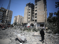 Palestinians are walking in front of a building damaged by Israeli bombardment in Nuseirat in the central Gaza Strip, on July 21, 2024, amid...