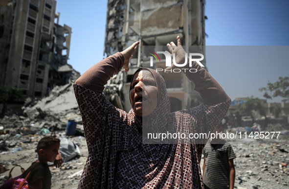 A Palestinian woman is gesturing near debris and destroyed vehicles in Nuseirat in the central Gaza Strip, on July 21, 2024, following an Is...