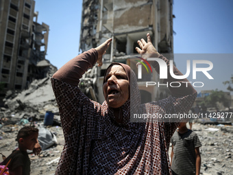 A Palestinian woman is gesturing near debris and destroyed vehicles in Nuseirat in the central Gaza Strip, on July 21, 2024, following an Is...