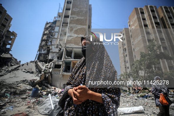 Palestinians are walking in front of a building damaged by Israeli bombardment in Nuseirat in the central Gaza Strip, on July 21, 2024, amid...