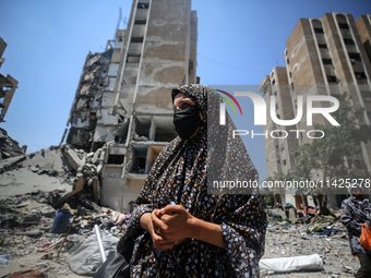 Palestinians are walking in front of a building damaged by Israeli bombardment in Nuseirat in the central Gaza Strip, on July 21, 2024, amid...