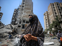 Palestinians are walking in front of a building damaged by Israeli bombardment in Nuseirat in the central Gaza Strip, on July 21, 2024, amid...