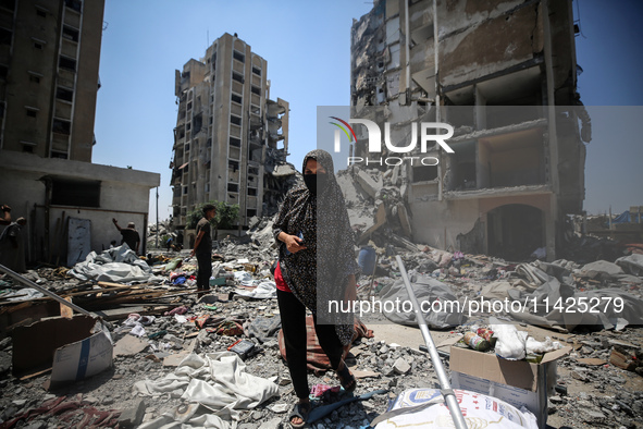 Palestinians are walking in front of a building damaged by Israeli bombardment in Nuseirat in the central Gaza Strip, on July 21, 2024, amid...