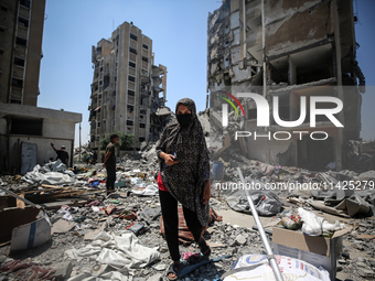 Palestinians are walking in front of a building damaged by Israeli bombardment in Nuseirat in the central Gaza Strip, on July 21, 2024, amid...