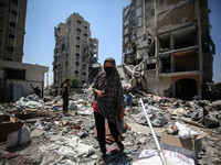 Palestinians are walking in front of a building damaged by Israeli bombardment in Nuseirat in the central Gaza Strip, on July 21, 2024, amid...