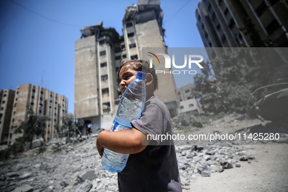 Palestinians are walking in front of a building damaged by Israeli bombardment in Nuseirat in the central Gaza Strip, on July 21, 2024, amid...