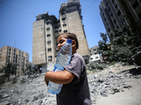 Palestinians are walking in front of a building damaged by Israeli bombardment in Nuseirat in the central Gaza Strip, on July 21, 2024, amid...