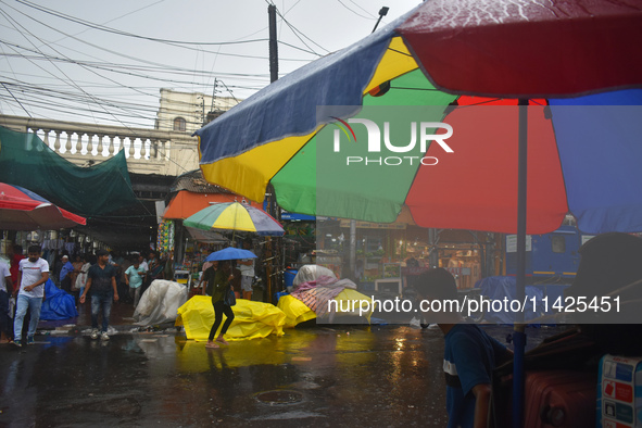 People are walking on the street in the rain in Kolkata, India, on July 21, 2024. 