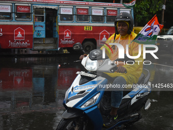 A person is riding a scooter in the rain in Kolkata, India, on July 21, 2024. (