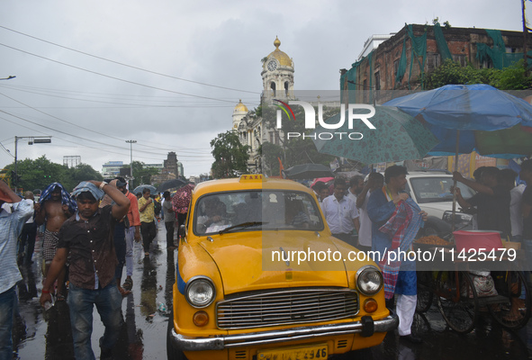 People are walking on the street in the rain in Kolkata, India, on July 21, 2024. 