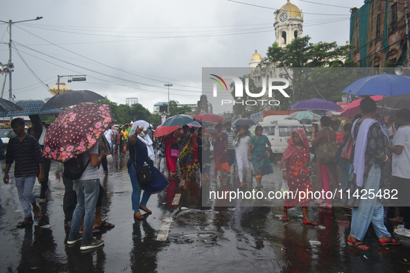 People are walking on the street in the rain in Kolkata, India, on July 21, 2024. 