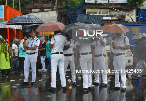 Kolkata police persons are using umbrellas while standing on the street during the monsoon in Kolkata, India, on July 21, 2024. 