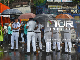 Kolkata police persons are using umbrellas while standing on the street during the monsoon in Kolkata, India, on July 21, 2024. (