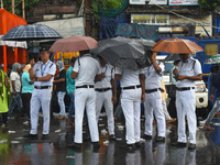 Kolkata police persons are using umbrellas while standing on the street during the monsoon in Kolkata, India, on July 21, 2024. (