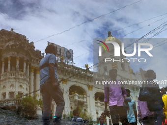 People are walking on the street reflected in a puddle of rainwater in the monsoon in Kolkata, India, on July 21, 2024. (