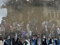 People are walking on the street reflected in a puddle of rainwater in the monsoon in Kolkata, India, on July 21, 2024. (