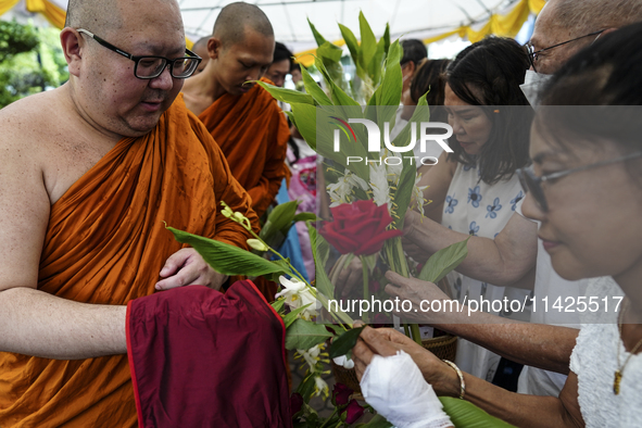 Thais are offering flowers to Buddhist monks during a floral merit-making ceremony, known as 'tak bat dok mai', at Rama IX Golden Jubilee Te...