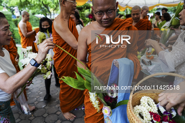 Thais are offering flowers to Buddhist monks during a floral merit-making ceremony, known as 'tak bat dok mai', at Rama IX Golden Jubilee Te...