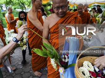 Thais are offering flowers to Buddhist monks during a floral merit-making ceremony, known as 'tak bat dok mai', at Rama IX Golden Jubilee Te...