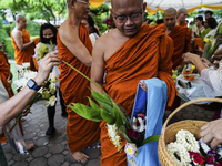 Thais are offering flowers to Buddhist monks during a floral merit-making ceremony, known as 'tak bat dok mai', at Rama IX Golden Jubilee Te...