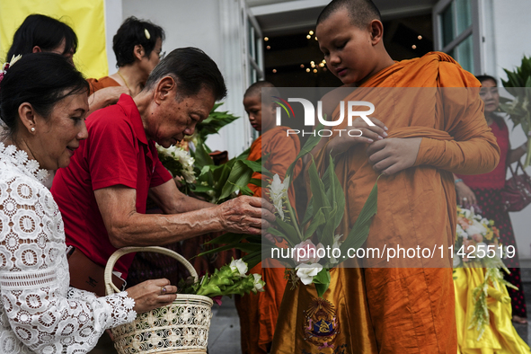 Thais are offering flowers to Buddhist monks during a floral merit-making ceremony, known as 'tak bat dok mai', at Rama IX Golden Jubilee Te...