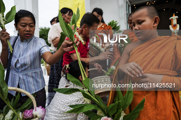 Thais are offering flowers to Buddhist monks during a floral merit-making ceremony, known as 'tak bat dok mai', at Rama IX Golden Jubilee Te...