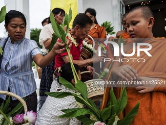 Thais are offering flowers to Buddhist monks during a floral merit-making ceremony, known as 'tak bat dok mai', at Rama IX Golden Jubilee Te...