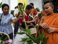 Thais are offering flowers to Buddhist monks during a floral merit-making ceremony, known as 'tak bat dok mai', at Rama IX Golden Jubilee Te...