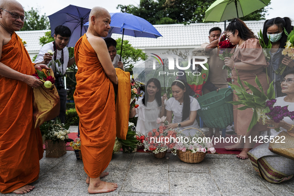 Thais are offering flowers to Buddhist monks during a floral merit-making ceremony, known as 'tak bat dok mai', at Rama IX Golden Jubilee Te...