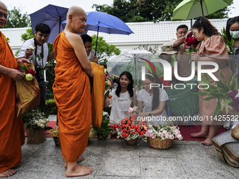 Thais are offering flowers to Buddhist monks during a floral merit-making ceremony, known as 'tak bat dok mai', at Rama IX Golden Jubilee Te...