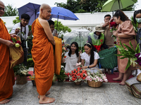 Thais are offering flowers to Buddhist monks during a floral merit-making ceremony, known as 'tak bat dok mai', at Rama IX Golden Jubilee Te...