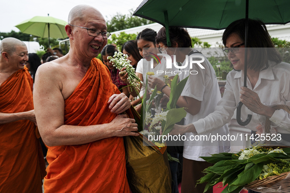 Thais are offering flowers to Buddhist monks during a floral merit-making ceremony, known as 'tak bat dok mai', at Rama IX Golden Jubilee Te...