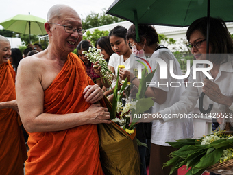 Thais are offering flowers to Buddhist monks during a floral merit-making ceremony, known as 'tak bat dok mai', at Rama IX Golden Jubilee Te...