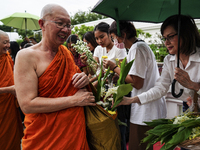 Thais are offering flowers to Buddhist monks during a floral merit-making ceremony, known as 'tak bat dok mai', at Rama IX Golden Jubilee Te...