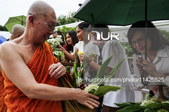 Thais are offering flowers to Buddhist monks during a floral merit-making ceremony, known as 'tak bat dok mai', at Rama IX Golden Jubilee Te...