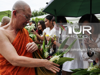 Thais are offering flowers to Buddhist monks during a floral merit-making ceremony, known as 'tak bat dok mai', at Rama IX Golden Jubilee Te...