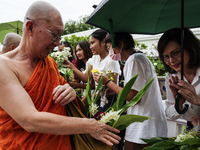 Thais are offering flowers to Buddhist monks during a floral merit-making ceremony, known as 'tak bat dok mai', at Rama IX Golden Jubilee Te...