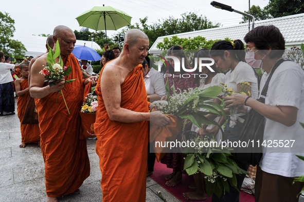 Thais are offering flowers to Buddhist monks during a floral merit-making ceremony, known as 'tak bat dok mai', at Rama IX Golden Jubilee Te...