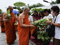 Thais are offering flowers to Buddhist monks during a floral merit-making ceremony, known as 'tak bat dok mai', at Rama IX Golden Jubilee Te...