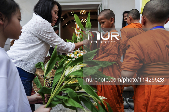 Thais are offering flowers to Buddhist monks during a floral merit-making ceremony, known as 'tak bat dok mai', at Rama IX Golden Jubilee Te...