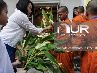 Thais are offering flowers to Buddhist monks during a floral merit-making ceremony, known as 'tak bat dok mai', at Rama IX Golden Jubilee Te...