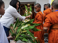 Thais are offering flowers to Buddhist monks during a floral merit-making ceremony, known as 'tak bat dok mai', at Rama IX Golden Jubilee Te...