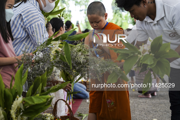 Thais are offering flowers to Buddhist monks during a floral merit-making ceremony, known as 'tak bat dok mai', at Rama IX Golden Jubilee Te...