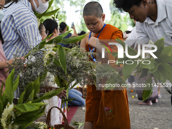 Thais are offering flowers to Buddhist monks during a floral merit-making ceremony, known as 'tak bat dok mai', at Rama IX Golden Jubilee Te...